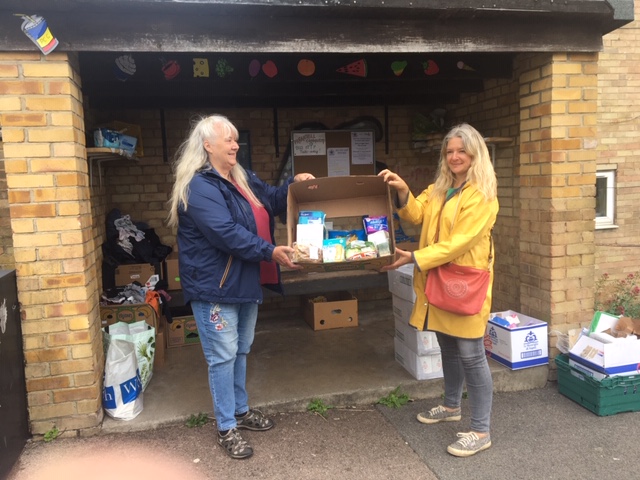 Jaqui Smith (Left) Chair of the Paganhill Community Group) receives the first of many food donations from Amanda-Jane Strover of the Stroud District Foodbank for the Paganhill Bus Stop Shop